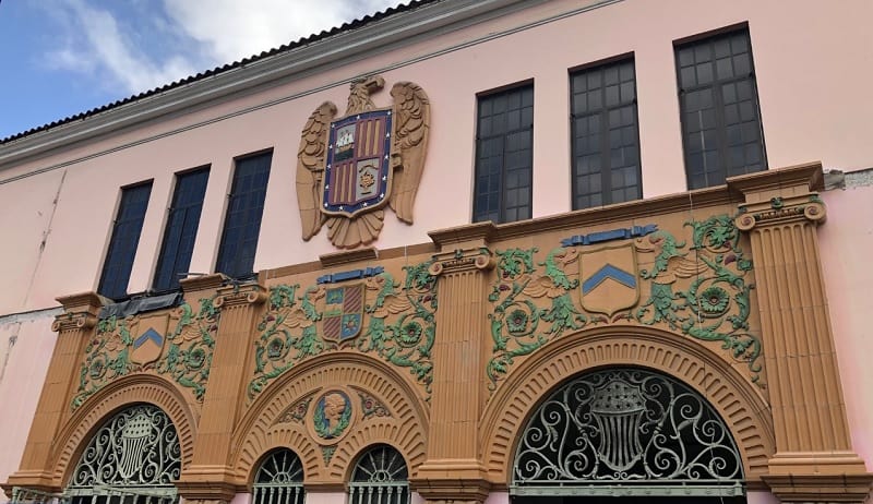 The rear of the US Customs building in Puerto Rico is pink with terra cotta designs in blue and green featuring a large eagle with a shield