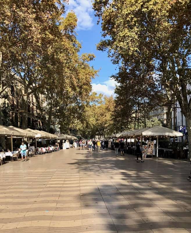 Barcelona's broad pedestrian boulevard of La Rambla is lined with restaurants and shops, and flanked by tall leafy trees