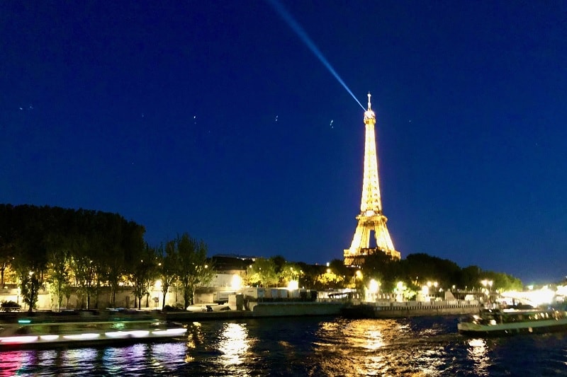 The Eiffel Tower illuminated at night reflected in the Seine river is one of the best things to see on a night tour of Paris!