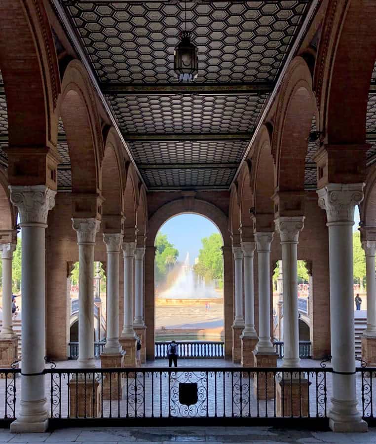 Arched arcade with a view of a fountain at the Seville Plaza de Espana.